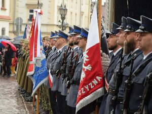 stojący w szeregu umundurowani funkcjonariusze Służby Więziennej, Policji i Wojska, wraz ze sztandarami