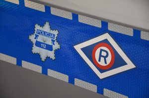 Gwiazda policyjna i logo Wydziału Ruchu Drogowego na odblasku umieszczonym na drzwiach radiowozu.