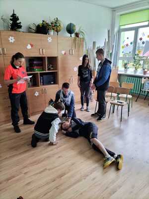 Na zdjęciu osoby biorące udział w turnieju ruchu drogowego. Uczestnicy udzielający pomocy osobie poszkodowanej- ćwiczenia.