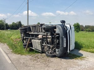 Pojazd marki Iveco leży na chodniku na lewym boku. Tył samochodu znajduje się częściowo na przydrożnym rowem.