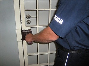 Umundurowany policjant zamykający kraty do policyjnego aresztu
