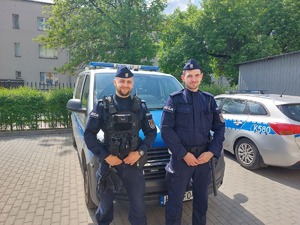 Wizerunek policjantów na tle radiowozu.