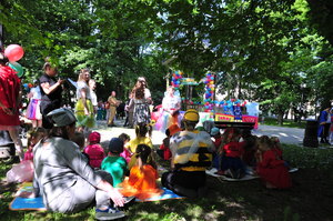 Dzieci oraz przedszkolanki przebrane za bajkowe postacie siedzą na trawie