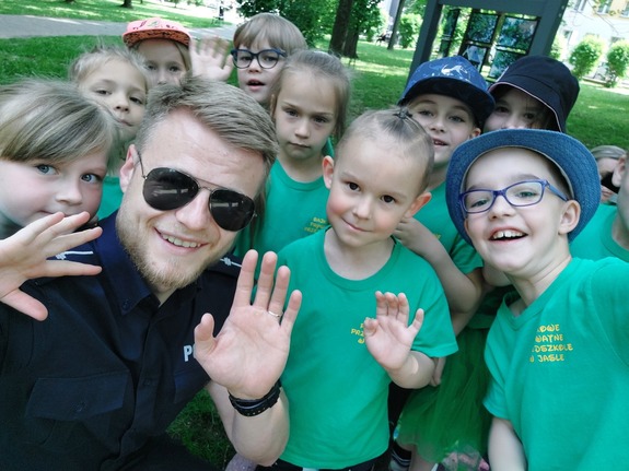 Rzecznik jasielskiej policji robiący sobie selfie z dziećmi w zielonych koszulkach