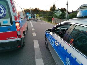 na ulicy stoi radiowóz osobowy i karetka w tle dwa rowery położone na ścieżce rowerowej