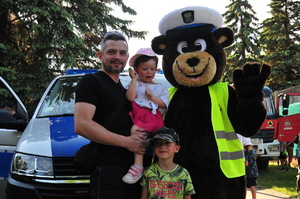 Maskotka jasielskiej policji wraz z dwójką dzieci i ich ojcem przed radiowozem