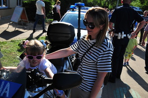Dziewczynka na policyjnym motocyklu. Obok stoi jej mama.