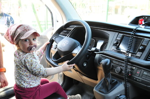 Mała dziewczynka ze smoczkiem w buzi siedząca za kierownicą radiowozu