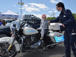 umundurowana policjantka stojąca przy motocyklu na którym siedzi chłopiec