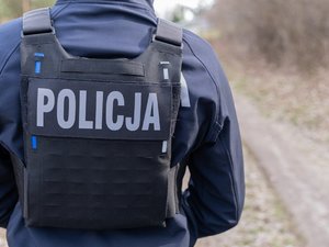 Zdjęcie przedstawia umundurowanego funkcjonariusza Policji. Ma na sobie kamizelkę z napisem "policja".