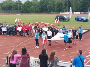 Policjanci, strażacy i uczestnicy zawodów trzymający flagę Olimpiad Specjalnych.