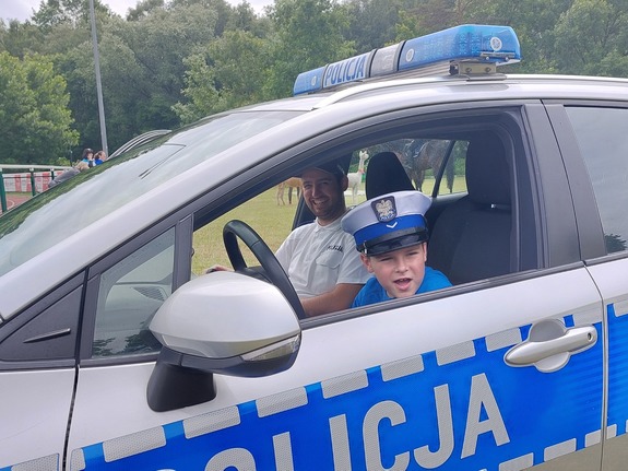 Chłopiec za kierownicą radiowozu policyjnego.