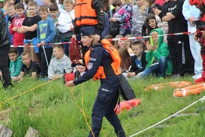 Na zdjęciu policjanta rzuca linę ratunkowa, w tle uczestnicy spotkania.