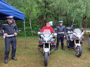 chłopiec siedzący na motocyklu, obok policjanci