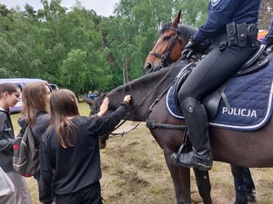 policjanci na koniach, obok dzieci głaskające jednego z koni