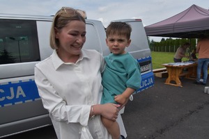 radiowóz policyjny i mama z dzieckiem na rękach