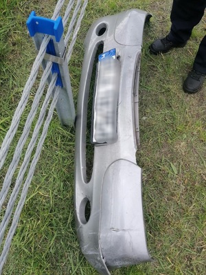 na trawniku leży przedni zderzak osobowego pojazdu przed zderzakiem bariera energochłonna