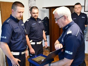Komendant wręcza w gabinecie policjantom grawerton