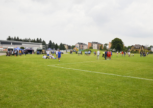 Fragment boiska. W dalekim tle zawodnicy kliku drużyn oraz stoiska służb mundurowych
