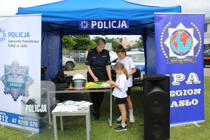 Stoisko policyjne, na którym policjantka rozmawia z dwoma dziewczynkami