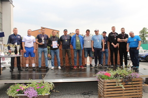 Zawodnicy SOK  z pucharem, dyplomem oraz medalami na szyi oraz organizator, komendanci jasielskiej policji i straży pożarnej pozujący do zdjęcia na scenie podczas ceremonii wręczania nagród.