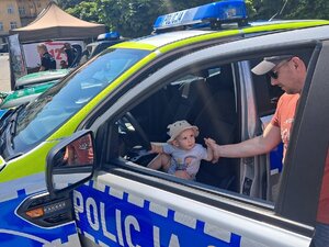 mały chłopczyk w samochodzie policyjnym siedzący za kierownicą