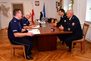Komendant Wojewódzki Policji w Rzeszowie podpisuje porozumienie w gabinecie przy stole. Na zdjęciu Komendant Wojewódzki Policji i zaproszeni goście w trakcie podpisywania porozumienia