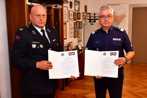 Komendant Wojewódzki Policji w Rzeszowie podpisuje porozumienie w gabinecie przy stole. Na zdjęciu Komendant Wojewódzki Policji i zaproszeni goście w trakcie podpisywania porozumienia