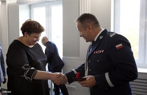 Zdjęcie przedstawia wnętrze sali, w której ustawieni są pracownicy Policji, umundurowani policjanci, poczet sztandarowy. Policjanci i pracownicy odbierają odznaczenia od Komendanta.