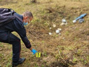 umundurowany  funkcjonariusz umieszcza na ziemi oznaczenie numeryczne śladu