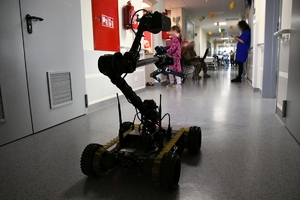 Policyjni kontrterroryśći wraz z policyjnym robotem wręczają dzieciom w szpitalu  prezenty.