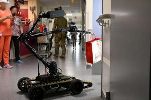 Policyjni kontrterroryśći wraz z policyjnym robotem wręczają dzieciom w szpitalu  prezenty.