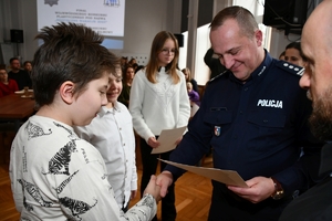 Zastępca Komendanta Wojewódzkiego Policji w Rzeszowie wraz z zaproszonymi gośćmi podczas wręczenia nagród laureatom konkursu w auli Komendy Wojewódzkiej Policji w Rzeszowie.