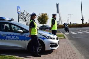 Policjanci stojący przy radiowozie, przy ulicy