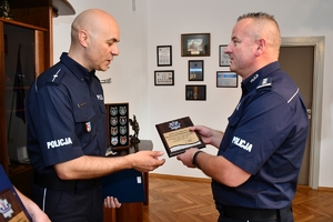 Komendant Wojewódzki Policji w Rzeszowie insp. Jarosław Tokarczyk gratuluje najlepszym ratownikom policyjnym. Po prawej komendant, po lewej dwaj nagrodzeni policjanci.
