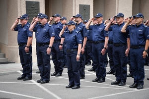 Kierownictwo KWP w Rzeszowie i policjanci garnizonu oddają hołd zmarłemu żołnierzowi. Policjanci stoją w szyku przed budynkiem komendy, za nimi ustawione dwa radiowozy.