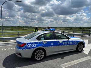 Policjanci prowadza pomiar odległości miedzy pojazdami, w tle autostrada
