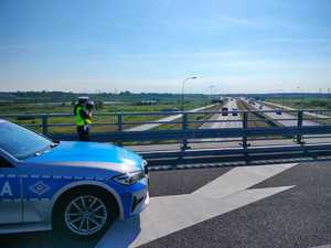 Policjanci prowadza pomiar odległości miedzy pojazdami, w tle autostrada