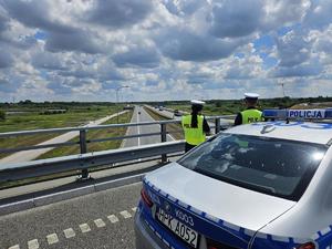 Policjanci prowadza pomiar odległości miedzy pojazdami, w tle autostrada