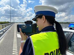 Policjanci prowadza pomiar odległości miedzy pojazdami, w tle autostrada