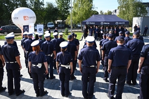 Policjanci i zaproszeni goście podczas uroczystości otwarcia komisariatu. Policjanci stoją na parkingu przed budynkiem.