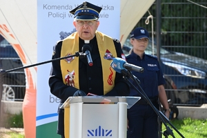 Policjanci i zaproszeni goście podczas uroczystości otwarcia komisariatu. Policjanci stoją na parkingu przed budynkiem.