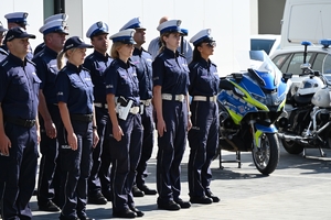 Policjanci i zaproszeni goście podczas uroczystości otwarcia komisariatu. Policjanci stoją na parkingu przed budynkiem.