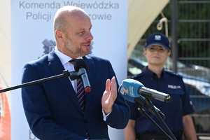 Policjanci i zaproszeni goście podczas uroczystości otwarcia komisariatu. Policjanci stoją na parkingu przed budynkiem.