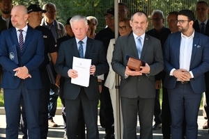 Policjanci i zaproszeni goście podczas uroczystości otwarcia komisariatu. Policjanci stoją na parkingu przed budynkiem.