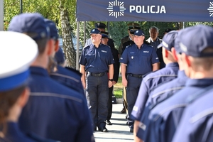 Policjanci i zaproszeni goście podczas uroczystości otwarcia komisariatu. Policjanci stoją na parkingu przed budynkiem.