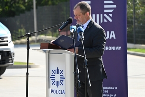 Policjanci i zaproszeni goście podczas uroczystości otwarcia komisariatu. Policjanci stoją na parkingu przed budynkiem.