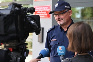 Policjanci i zaproszeni goście podczas uroczystości otwarcia komisariatu. Policjanci stoją na parkingu przed budynkiem.