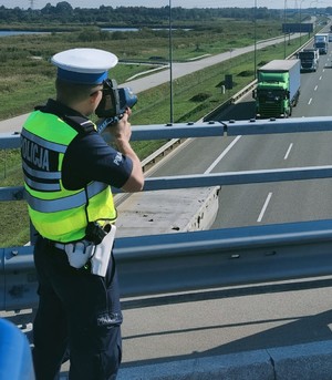 umundurowany policjant wykonujący  urządzeniem kontrole odległości pomiędzy pojazdami