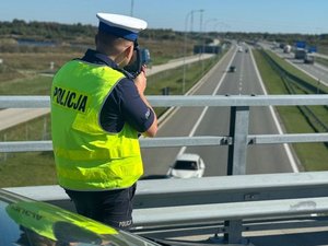 policjant w żółtej kamizelce z miernikiem prędkości